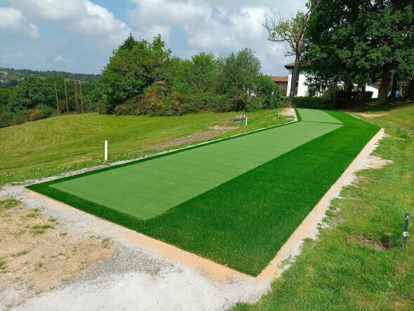 Charlotte Outdoor tee line consisting of one continuous green synthetic grass strip surrounded by trees